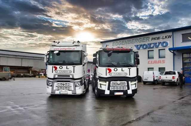 Zwei Renault-Sattelzugmaschinen vor der Halle, darüber die Schriftzüge Eggenberger PKW-LKW, Volvo und Claas