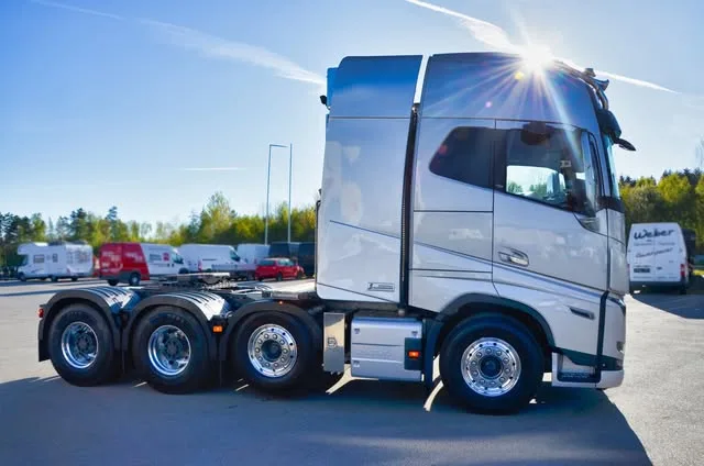 Silberne Volvo-Sattelzugmaschine mit vier Achsen im Gegenlicht auf dem Hof