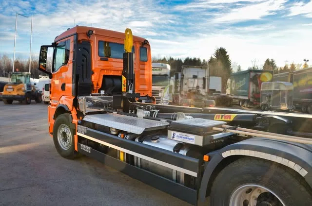Oranger LKW mit Hakenlift-Aufbau auf dem Hof