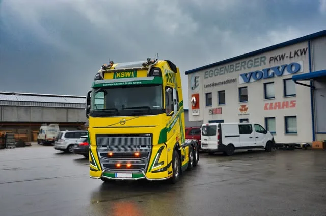 Gelber Volvo FH vor der Halle mit dem Schriftzug Eggenberger PKW-LKW und Volvo